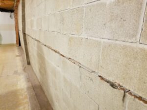 Bowed basement wall showing visible cracks and potential foundation issues, emphasizing the need for professional assessment and waterproofing solutions.