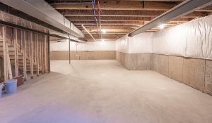 Empty basement space with concrete flooring and insulated walls, illustrating the importance of basement waterproofing for moisture prevention and structural integrity.