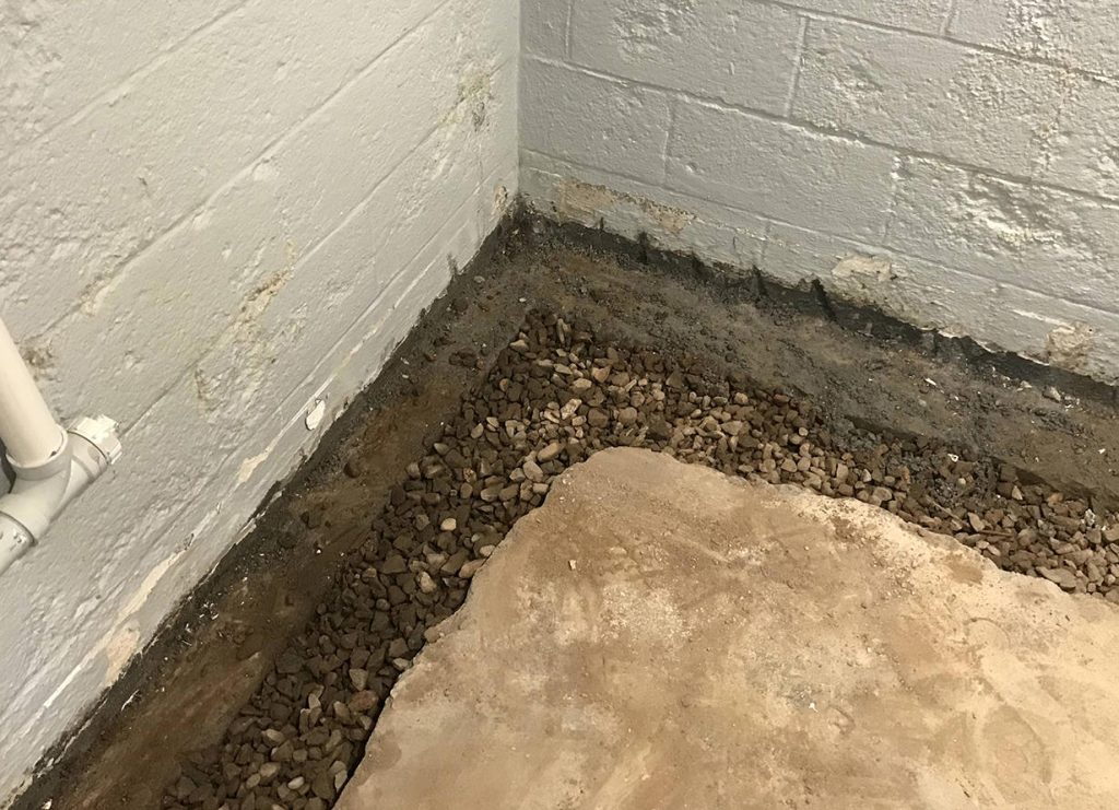 Basement corner showing gravel drainage system and exposed wall, illustrating essential waterproofing measures for preventing water intrusion.