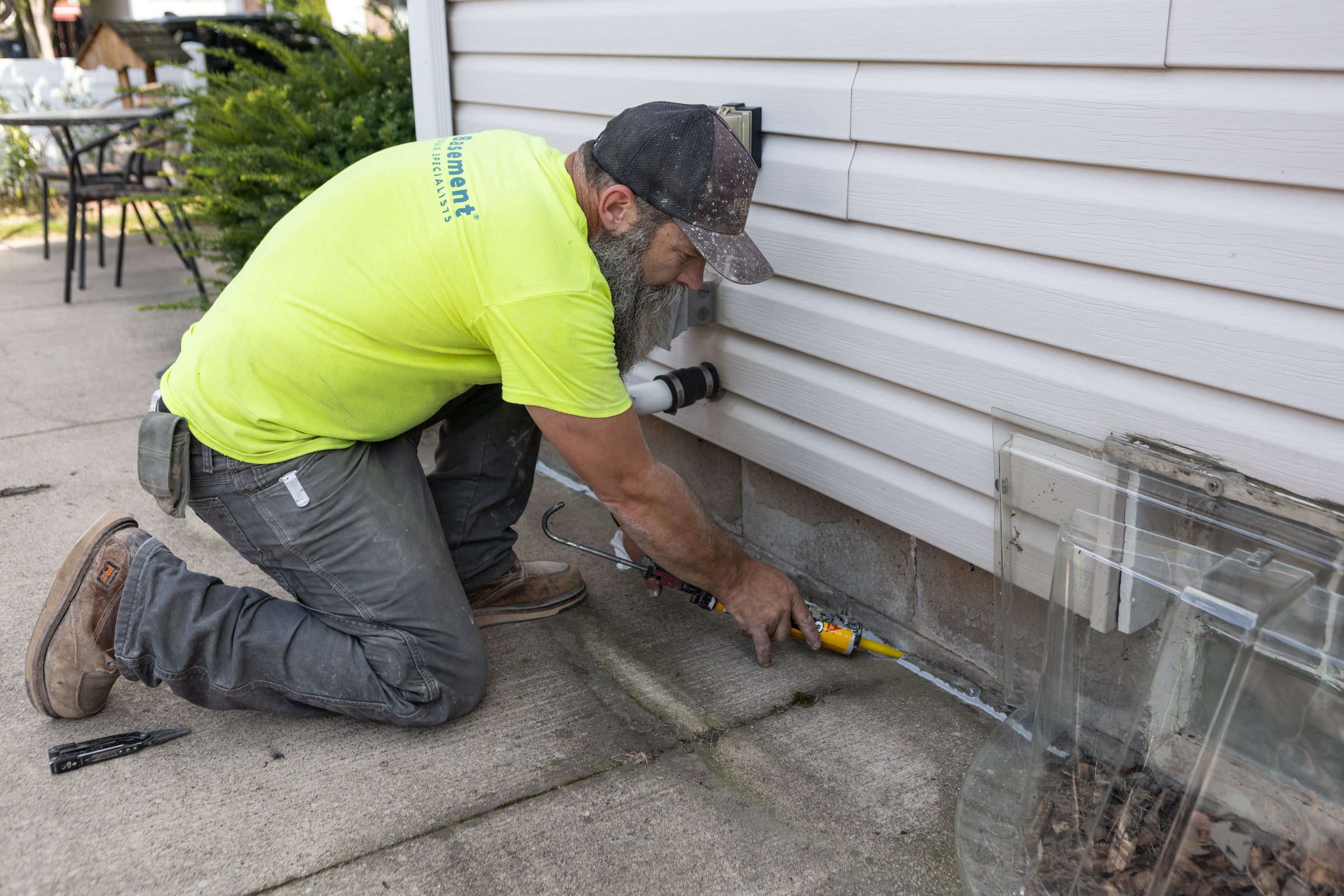 Contractor applying foundation crack repair sealant near basement wall, emphasizing expert techniques for preventing water and soil gas entry.