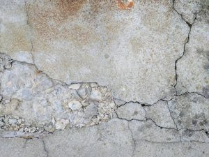 Cracked concrete surface highlighting structural damage, relevant to basement repair and foundation stability concerns.