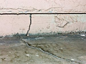 Cracked foundation wall and floor, indicating potential structural issues, relevant to foundation repair methods and home value preservation.