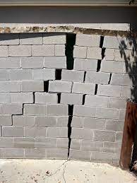 Cracked concrete block foundation wall indicating significant structural damage and potential water infiltration risks.