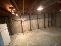 Basement interior showing exposed concrete walls, wooden beams, and a refrigerator, illustrating the importance of proper foundation maintenance and repair solutions offered by Basement Repair Specialists.