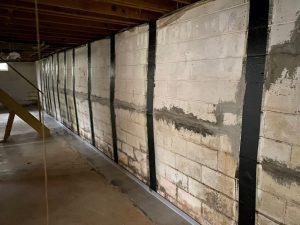 Bowed basement wall with carbon fiber straps installed for stabilization, illustrating wall repair techniques for foundation issues.