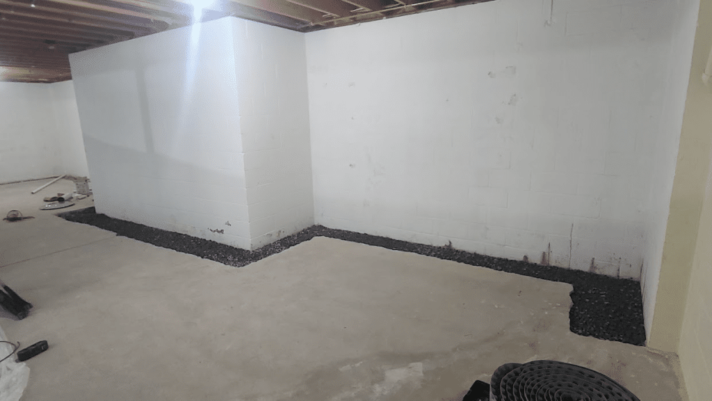 Basement interior showing prepared area with gravel along the walls, indicating waterproofing efforts for effective drainage and moisture control.