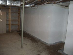 Basement interior with freshly sealed walls and floor, showcasing waterproofing measures to prevent water intrusion and moisture issues.