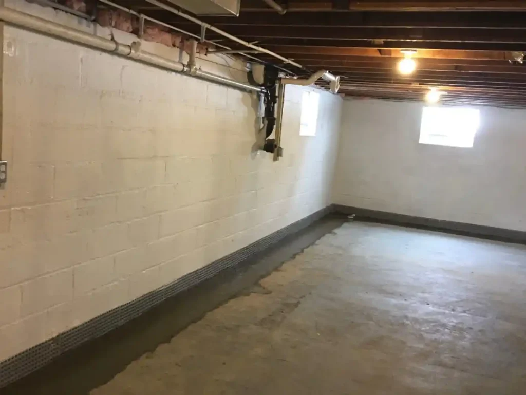 Basement interior featuring clean walls, concrete floor, and installed drain tile system for effective waterproofing and moisture control.