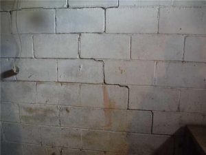 Cracked basement wall showing signs of foundation damage, highlighting the importance of timely repairs and preventative measures for home stability.