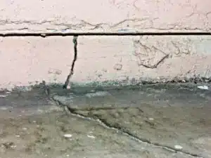 Crack in interior wall and floor indicating potential foundation damage, highlighting signs of structural distress and the need for repair.