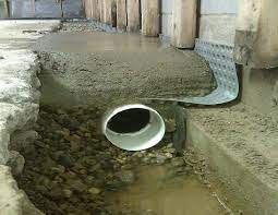 Basement drainage system with perforated pipe and gravel, illustrating essential waterproofing features for preventing water damage.