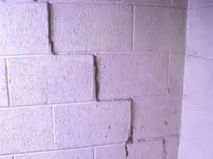 Stair-step cracks in a block foundation wall indicating potential foundation issues and structural distress.