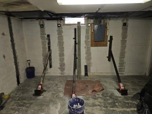 Basement wall repair with carbon fiber straps and steel wall anchors stabilizing bowed foundation walls