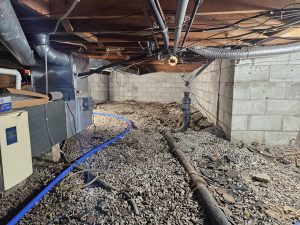 Crawl space with exposed soil, pipes, and moisture issues causing sagging floors and poor air quality