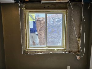 Basement egress window installation in Wisconsin with a new window framed into a concrete foundation wall